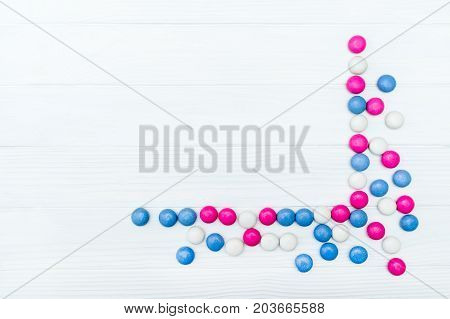 Frame from colorful mint coated candies texture on white wooden background. Top view. Copy space