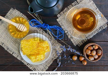 A cup of herbal tea honey honeycomb hazelnuts on a dark wooden background. Healthy foods. Proper nutrition.