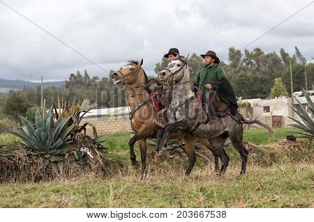 June 10 2017 Toacazo Ecuador: cowboys wearing traditional poncho riding their horses in the rain