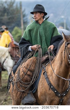 June 10 2017 Toacazo Ecuador: cowboy wearing poncho holding a lasso in the rain