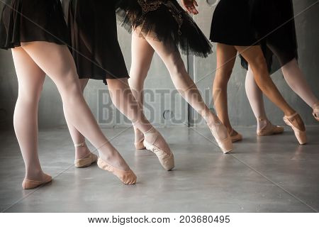 close-up of a young ballet dancer in black dresses white pantyhose and pointe shoes pull a sock