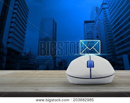 Mail flat icon with wireless computer mouse on wooden table over modern office city tower Contact us concept