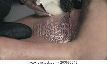 Extreme close up. Permanent make-up of dark circles under the eyes. Tattooing of dark circles in beauty clinic.