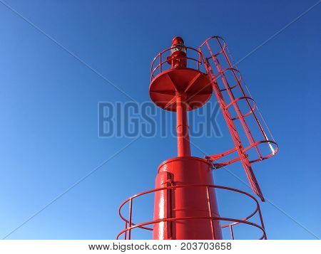 Red Lighthouse at port with blue sky .