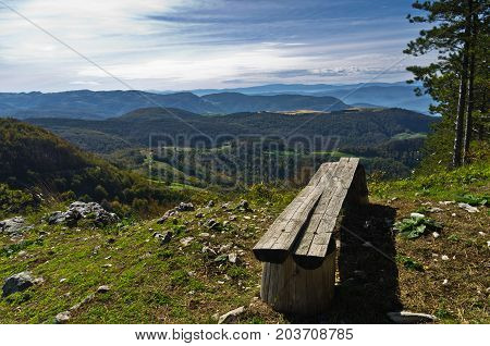 Viewpoint with a bench at mount Bobija, beautiful view of surrounding peaks, hills, meadows and colorful forests, west Serbia