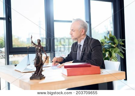 Mature Lawyer Sitting At Workplace