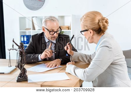 mature concentrated lawyers discussing contract in office