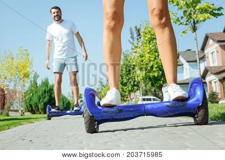 Testing new device. The focus being on the bare legs of a female standing on a blue hoverboard while her husband following her on the same hoverboard