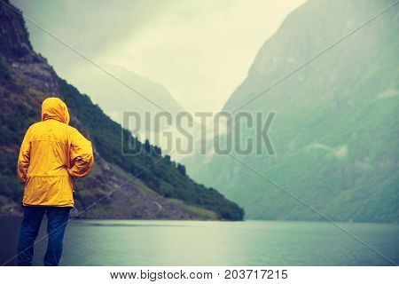 Tourism vacation and travel. Male tourist looking at mountains and fjord Sognefjord in Norway Scandinavia. Misty foggy day rainy weather