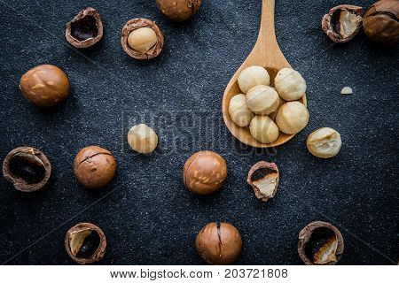 Close up The Macadamia nuts on dark black stone background superfood and healthy food concept overhead or top view shot