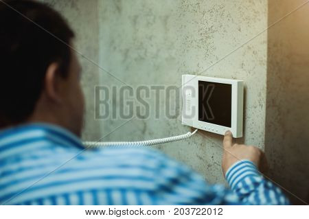 The man with his hand presses the button in the intercom