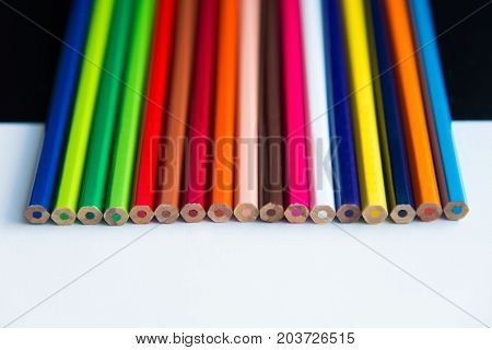 Multicolored pencils on a white background are arranged in a line