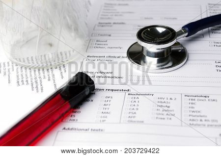 stethoscope beaker blood sample test tube and patient information form on desk heart healthcare technology medical diagnosis blood test medical report record and history patient concept