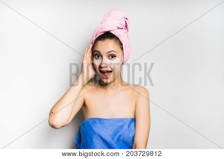A young woman in a towel on her head is surprised to scream after a bath. Isolated on white background