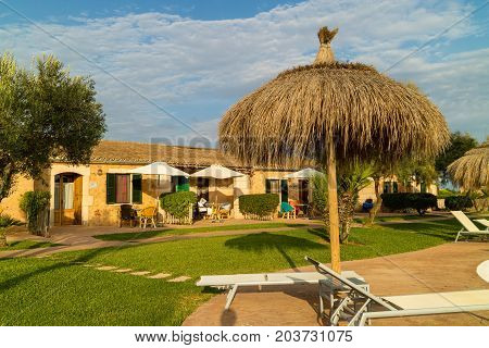 CAMPOS MALLORCA SPAIN - August 30 2017: Panorama of a swimming pool from a Mediterranean finca buildings built in traditional island style and garden with palm trees and orange trees. Balearic islands. Summer 2017.
