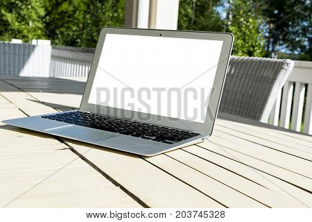 Wooden white office desk table with open blank laptop computer empty space. Front view with copy space. Silver laptop on wooden desk background