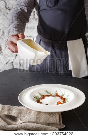 Waiter pouring broth to mushroom cream soup. Original restaurant serving of delicacy meal, copy space