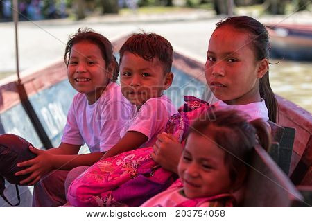 June 6 2017 Misahualli Ecuador: huaorani children lit by the light filtered by the colored tarp of the small boat on their way home from school