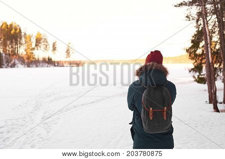 Active lifestyle hiking traveling and adventure concept. Scenic view of peaceful winter landscape of snowy fields and unrecognizable male in warm clothes walking on trail alone enjoying fresh air