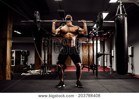 Muscular fitness man doing deadlift a barbell over his head in modern fitness center. Functional training. Snatch exercise