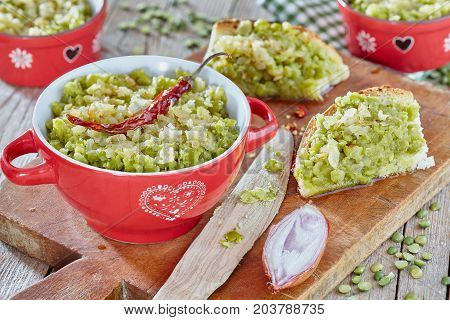 Cream of split green peas with sauce of oil and onions inside small pot and spread over bread slices.