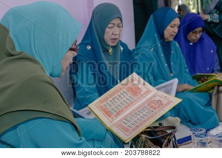 Labuan,Malaysia-Aug 30,2017:Muslim woman perform Quran recitation during Aqiqah ceremony in Labuan,Malaysia.Islamic traditions after a baby is born include shaving his head & sacrificing an animal.