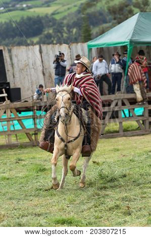 June 3 2017 Machachi Ecuador: young kechwa boy in traditional cowboy outfit working the lasso outdoors from horseback