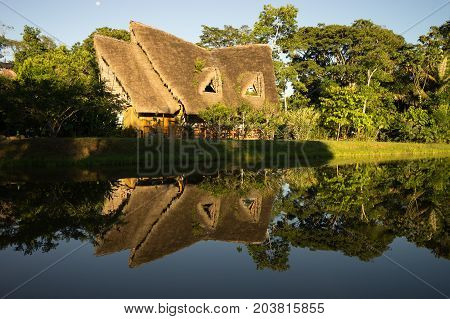 June 6 2017 Puerto Misahualli: eco lodge built from bamboo in the jungle reflecting into water at sunset