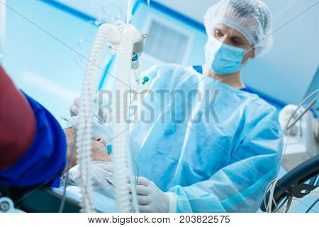 He is my colleague. Professional surgeon bowing head and being in sterile uniform while doing anesthesia