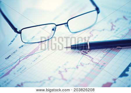 Pen and glasses on financial chart business concept analysis of sales plan business report business work station with paperwork