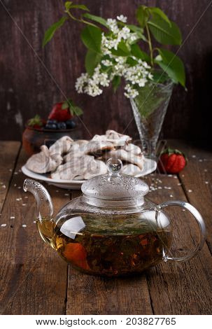 Herbal tea in glass teapot on wooden background. Rustic style.