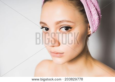 Portrait of a young girl after bathing, she stares at the camera, with a towel on her head
