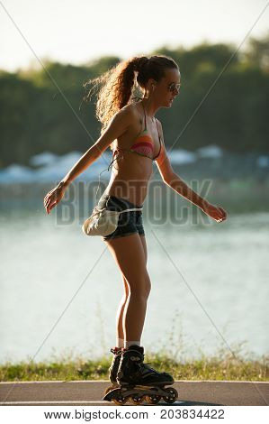 Girl In Bikini Swimwear And Jeans Shorts Drives Roller Skate