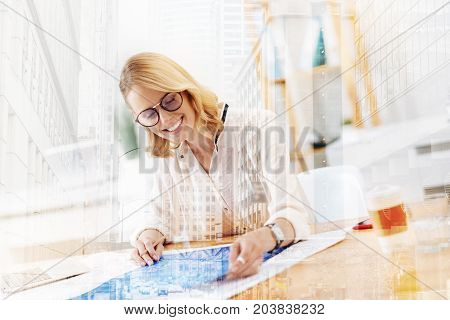 Undeniable success. Close up of pleasant cheerful designer occupied with work while being happy and pleased