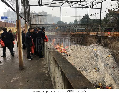 Wuhan China, 2 February 2017: Chinese people burning papers and incense at Guiyuan buddhist temple during chinese new year and huge ashes pile