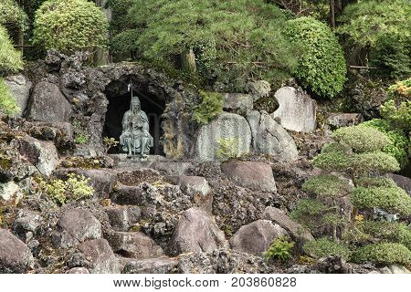bonsai trees growing outdoor in a garden on a with a statue sitting in a small cave Naritasan Temple Narita Japan 16.april 2012