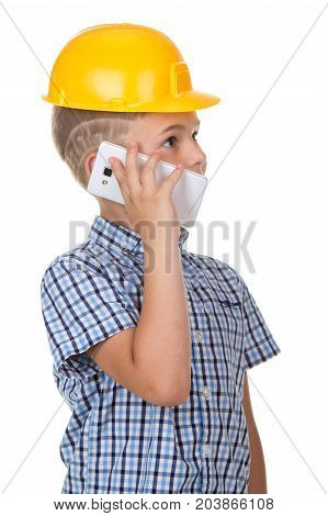 Cute builder boy speaks by phone, wearing yellow protectie helmet and blue checkered shirt. White background