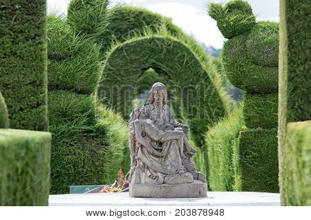 May 16 2017 Tulcan Ecuador: religious statue surrounded by green topiary in the famous cemetery