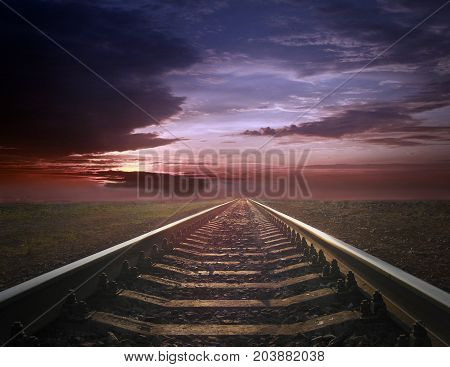 rails going away into the gloomy landscape. Black and white image with rails going away into the dark sky landscape