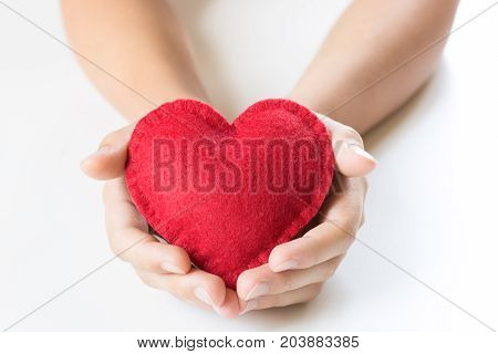 Red felt heart in childs hands on white background. View from above. Copy space.