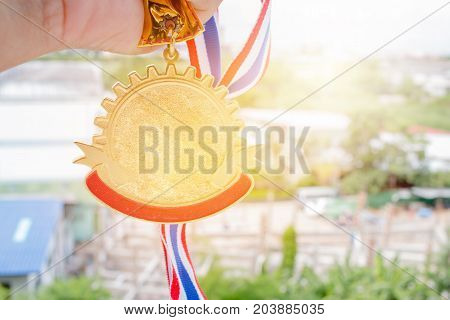 Winner hand holding golden medals to blur building background for show team success with their business Champion and Awards Concept