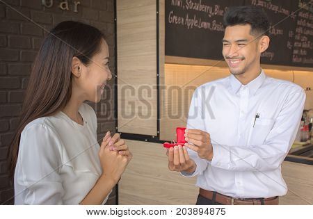 Young man Surprise girlfriend with a marriage proposal. The girl was surprised and happy.
