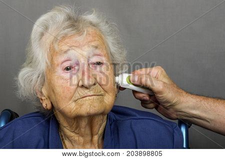 Senior Citizen having Temperature Checked.
Senior lady having a temperature check with a digital ear thermometer by a health care worker.