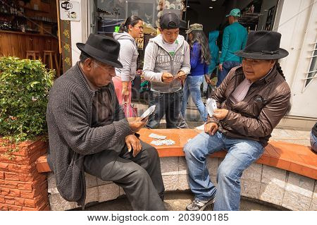 May 6 2017 Otavalo Ecuador: indigenous quechua men playing cards on the street in the Saturday market