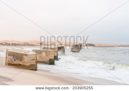 Pillars of the old railroad bridge over the mouth of the Swakop River at Swakopmund in the Namib Desert on the Atlantic Coast of Namibia