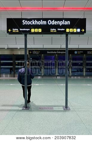 Stockholm Sweden - September 8 2017: A man on the platform leans with his back to the post bearing the sign with the Stockholm Odenplan station which is an underground commuter train station in Stockholm opened in July 2017.