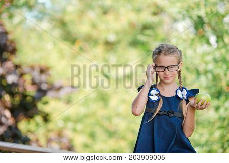 Adorable little school girl with notes and pencils outdoor.