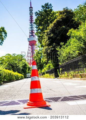 HAKONE, JAPAN - JULY 02, 2017: Close up of a orange cone in the streets with a huge red tower behind, at Hakone town.