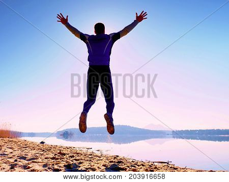 Jumping Man. Sportsman Crazy Jumping  And Jogging On Beach During The Sunrise