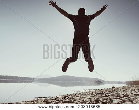 Jumping Man. Sportsman Crazy Jumping  And Jogging On Beach During The Sunrise